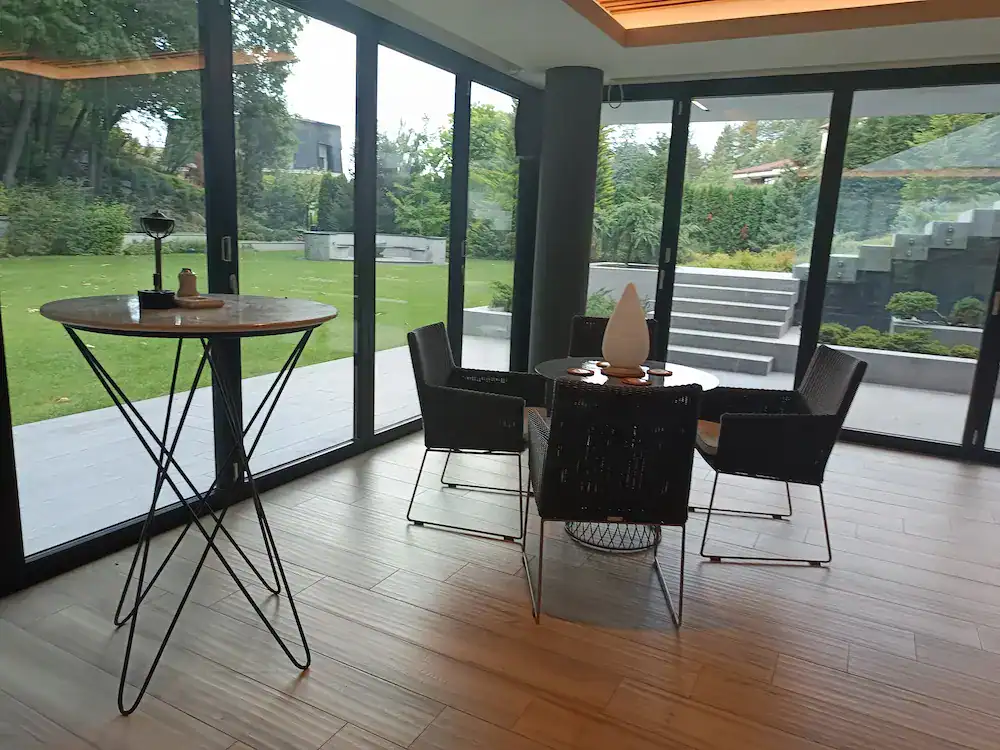 Contemporary dining room with glass sliding doors, garden view, and wooden flooring – completed construction and finishing project.