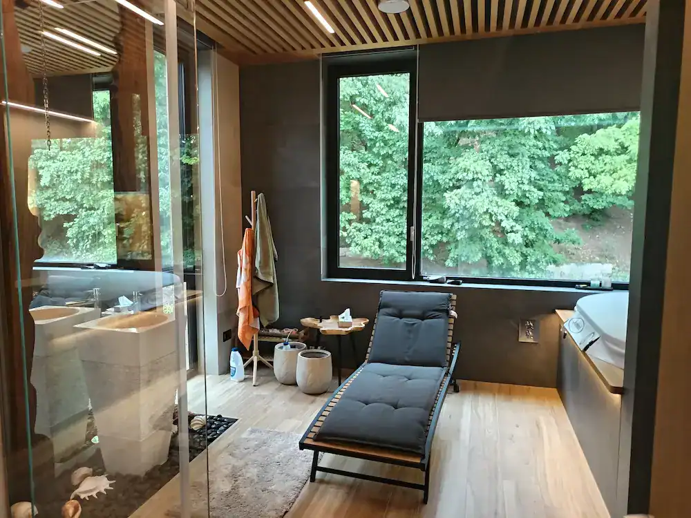 Contemporary home wellness and relaxation room with lounger, large window, and wooden flooring – completed construction and finishing project.